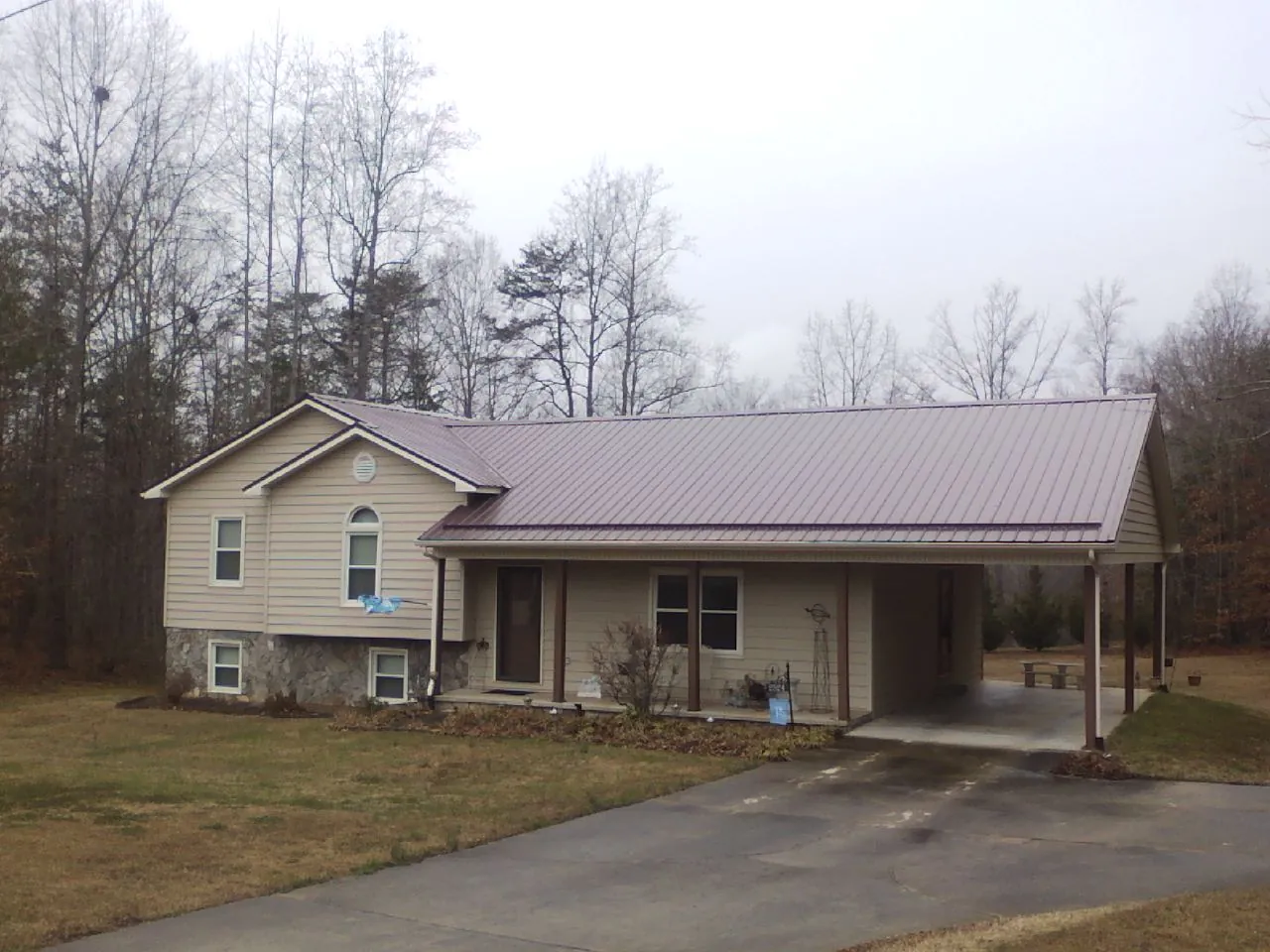 Burgundy metal roof on a tan split level home with an attached carport in Abbeville