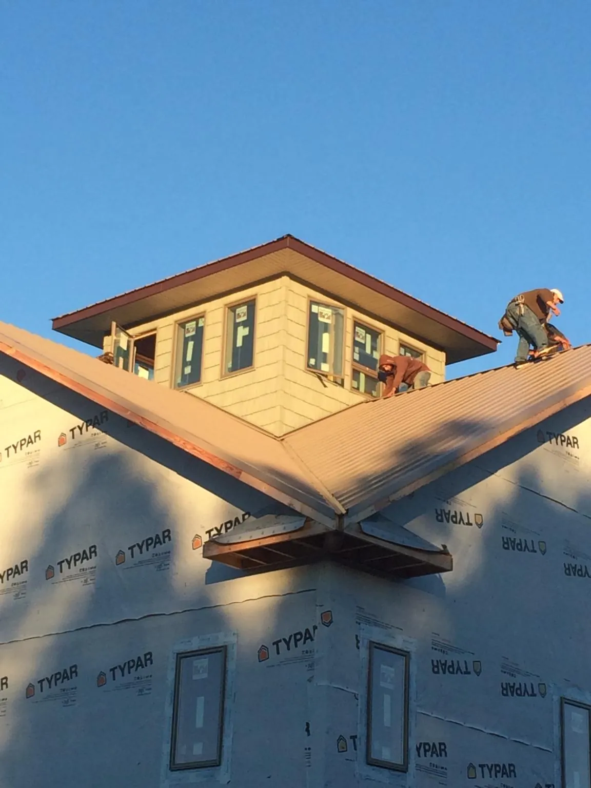 Roofers working around a rooftop cupola on a new metal roof at sunset — Roof Waterproofing in Abbeville by Roofing Brothers